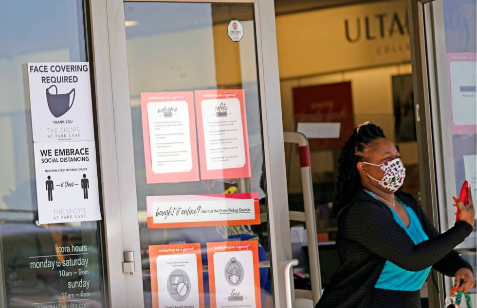 A customer exits a store with a mask required sign displayed, Tuesday, March 2, 2021, in Dallas ...