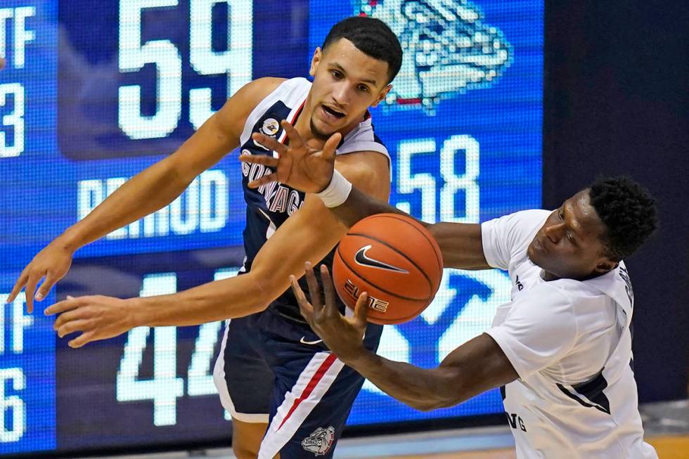 Gonzaga guard Jalen Suggs, rear, and BYU forward Gideon George, right, battle for a rebound in ...