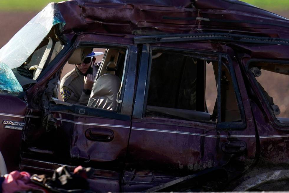 A California Highway Patrol officer examines the scene of a deadly crash in Holtville, Calif., ...