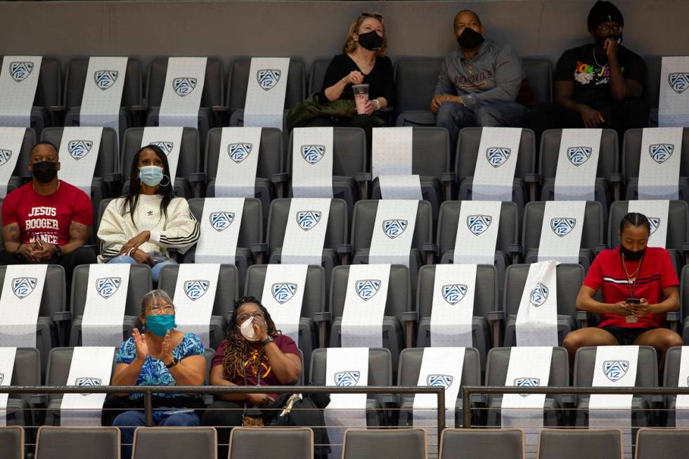 Fans sit socially distanced while watching the first half of an NCAA college basketball game be ...