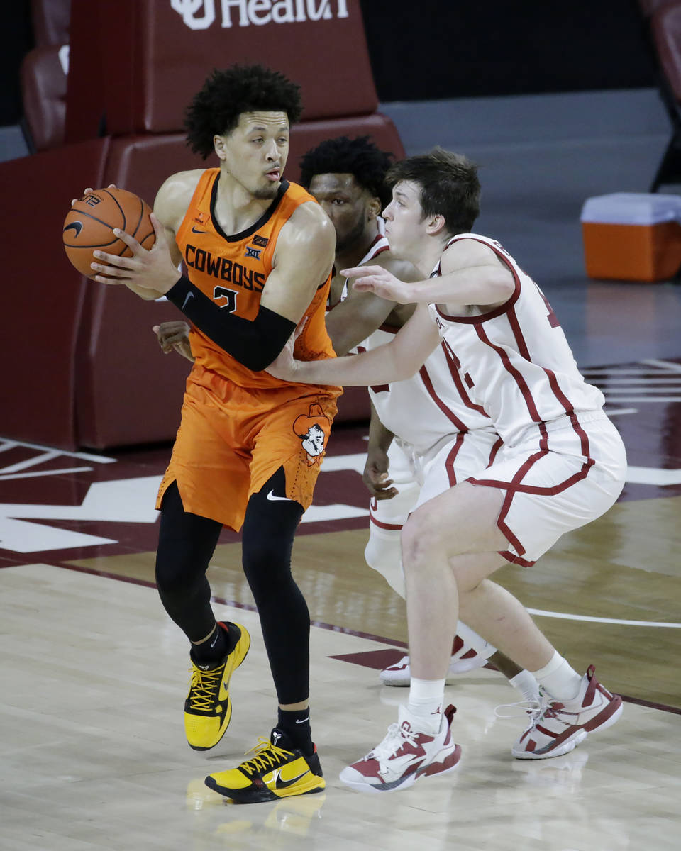 Oklahoma State guard Cade Cunningham (2) goes against Oklahoma guard Austin Reaves (12) and gua ...
