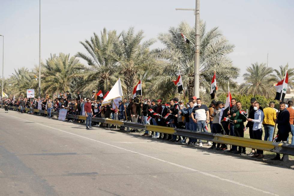 People stand by the road as they wait for Pope Francis, in Baghdad Iraq, Friday, March 5, 2021. ...