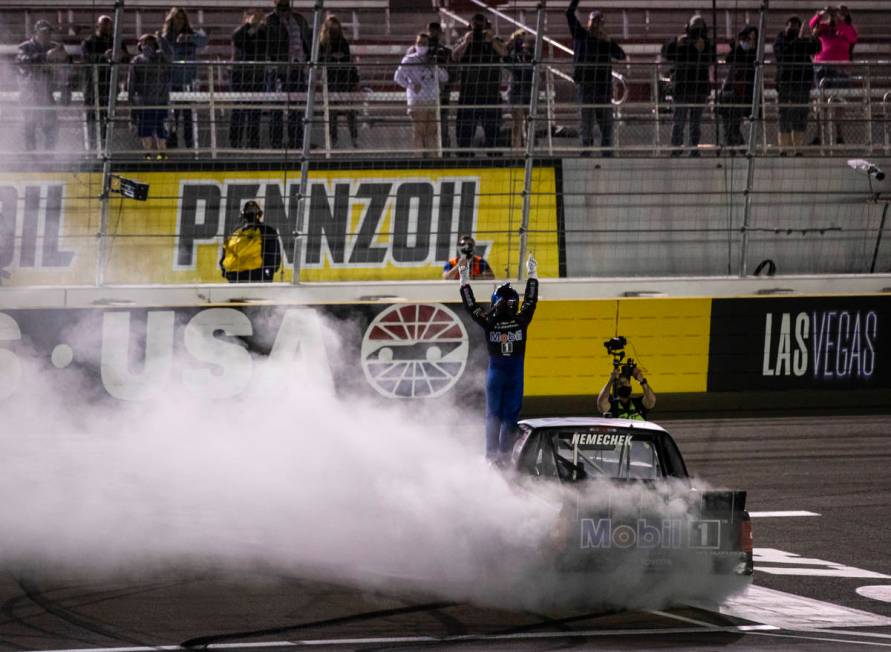 John Nemechek waves the checkered flag to fans after winning a NASCAR Camping World Truck Serie ...