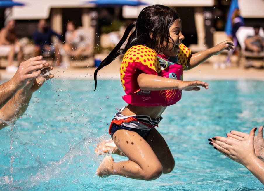 Tayla Swagger, 4, from Long Beach, Calif., leaps into her mothers arms in the pool at Aria on S ...