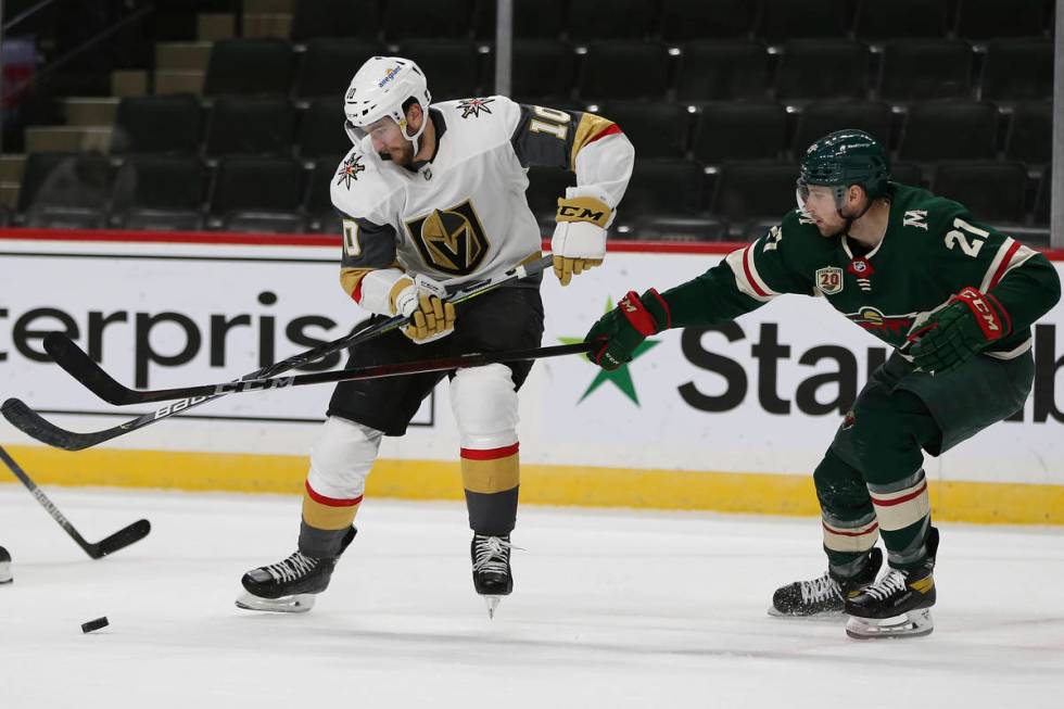 Minnesota Wild's Carson Soucy (21) and Vegas Golden Knights' Nicolas Roy (10) go after the puck ...