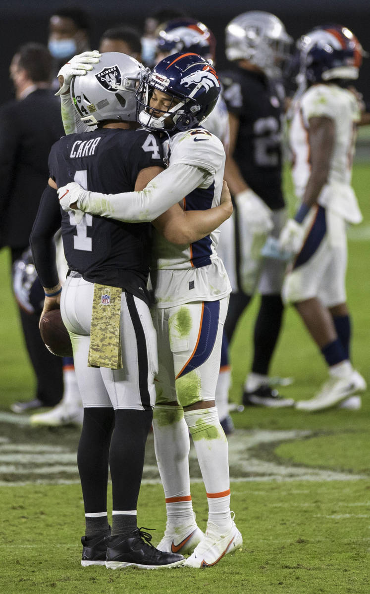 Las Vegas Raiders quarterback Derek Carr (4) hugs Denver Broncos cornerback A.J. Bouye (21) aft ...