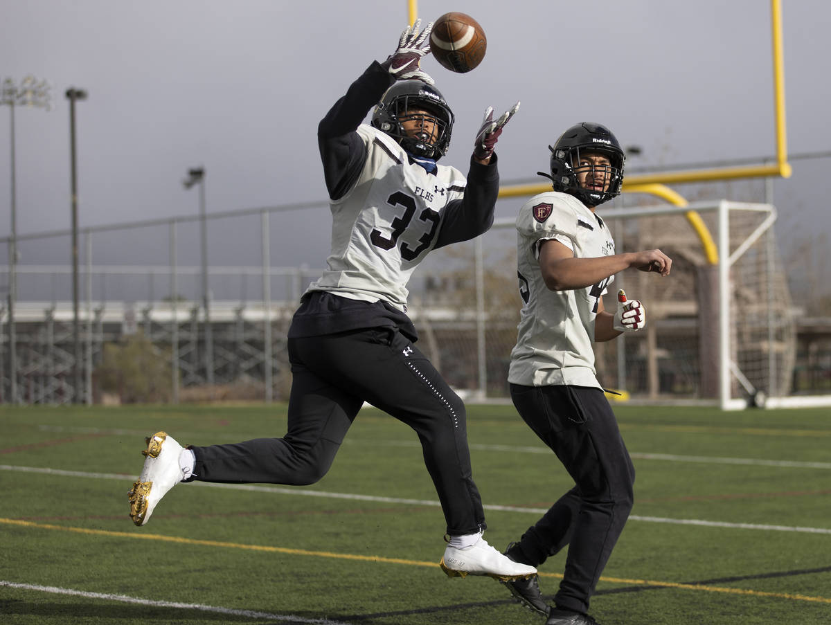 Faith Lutheran outside linebacker Leo Mendoza (33) makes a catch with inside linebacker Dean Ua ...