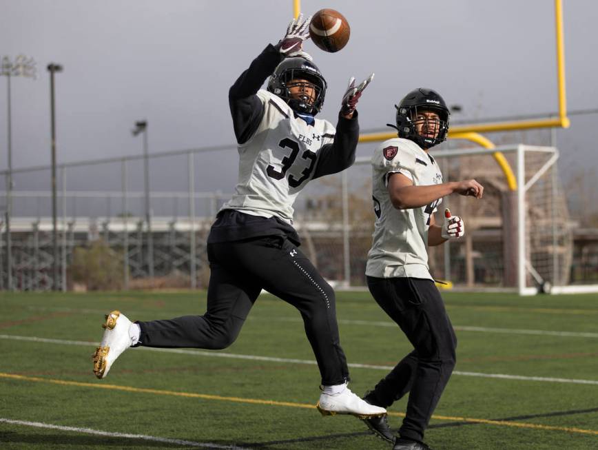 Faith Lutheran outside linebacker Leo Mendoza (33) makes a catch with inside linebacker Dean Ua ...