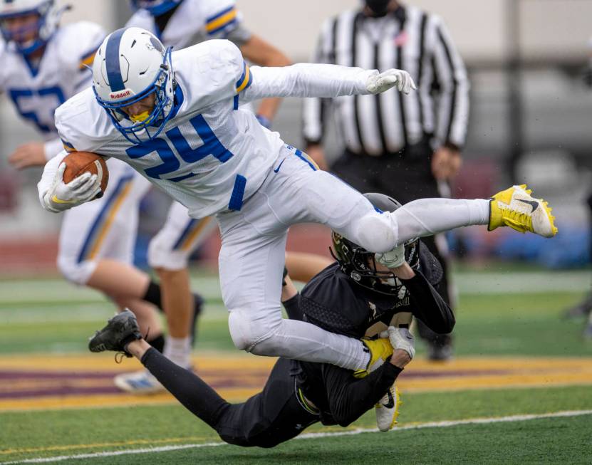 Moapa ValleyÕs Gunner Redd (24) is taken down in the backfield by Faith LutheranÕs Ch ...