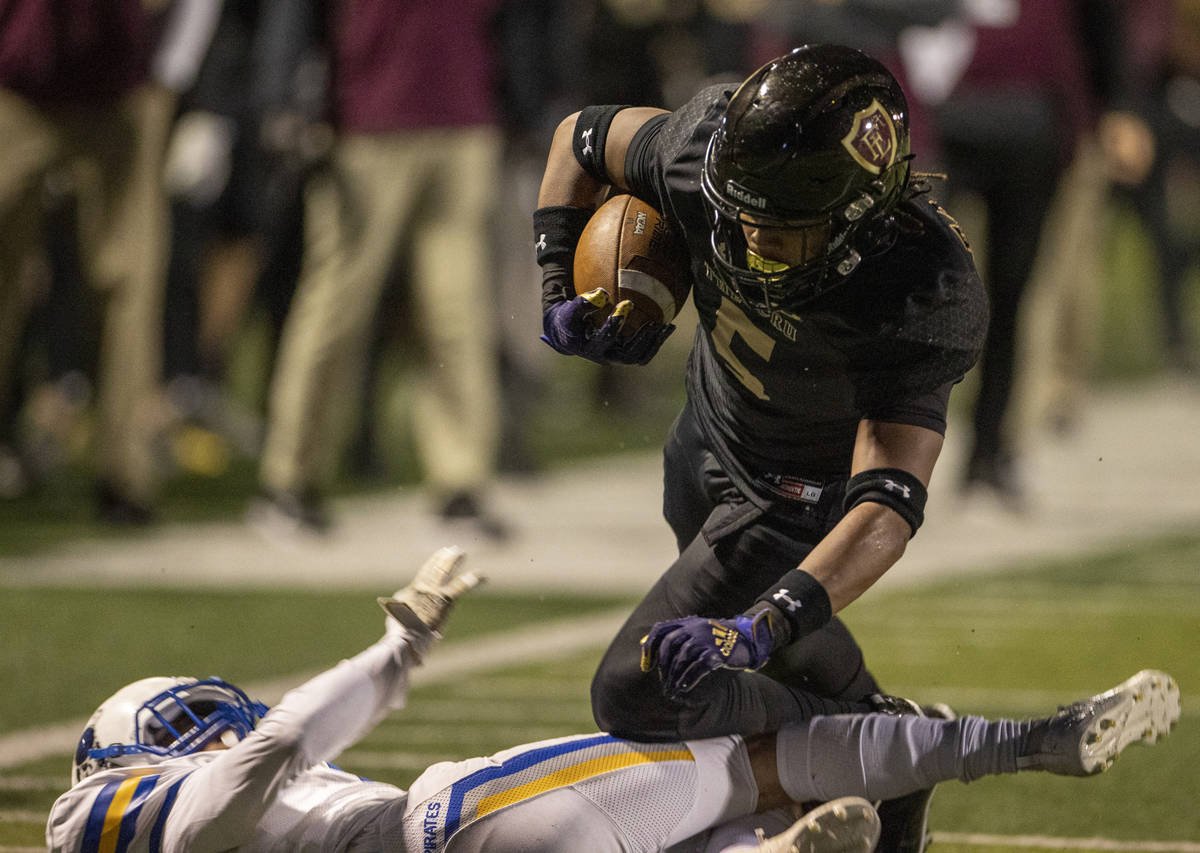 Faith LutheranÕs Jordan Pollard (5) goes over the top of Moapa ValleyÕs Chris Hoy (7) ...