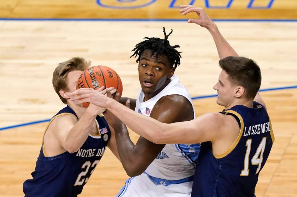 North Carolina forward Day'Ron Sharpe, center, gets pressured by Notre Dame guard Dane Goodwin ...