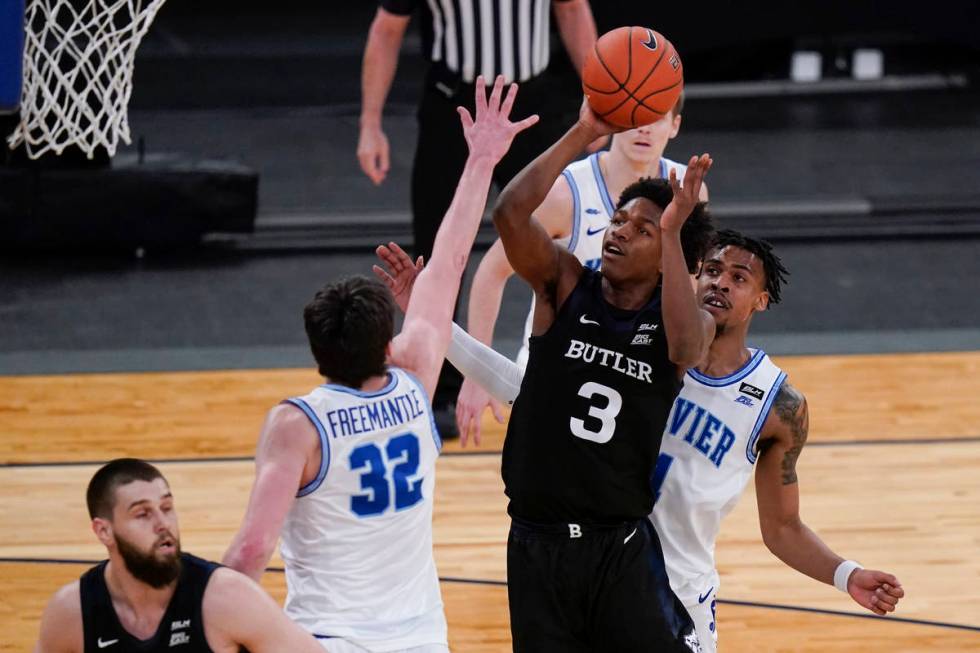 Butler's Chuck Harris, center, drives past Xavier's Paul Scruggs, right, to shoots over Zach Fr ...