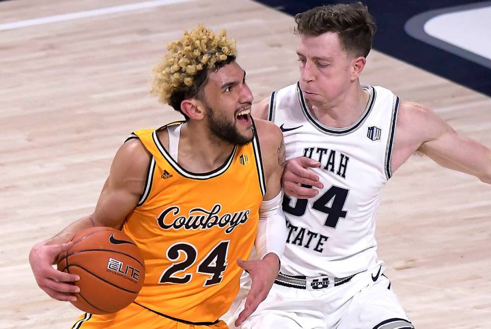 Wyoming guard Hunter Maldonado (24) drives to the baket as Utah State forward Justin Bean (34) ...