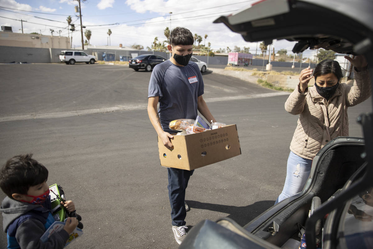 Volunteer Yahir Hernandez carries a box of food to the car of Yulissa Peña and her 4-year- ...