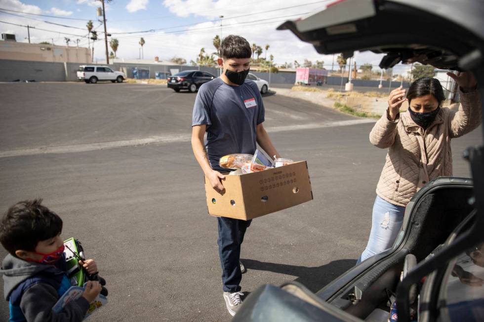 Volunteer Yahir Hernandez carries a box of food to the car of Yulissa Peña and her 4-year- ...