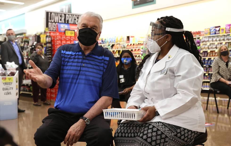 Gov. Steve Sisolak visits with Pharmacy Manager Trashelle Miro before receiving his COVID-19 va ...