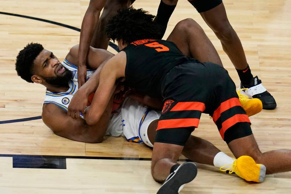 UCLA's Cody Riley, left, and Oregon State's Ethan Thompson (5) scramble for the ball during the ...