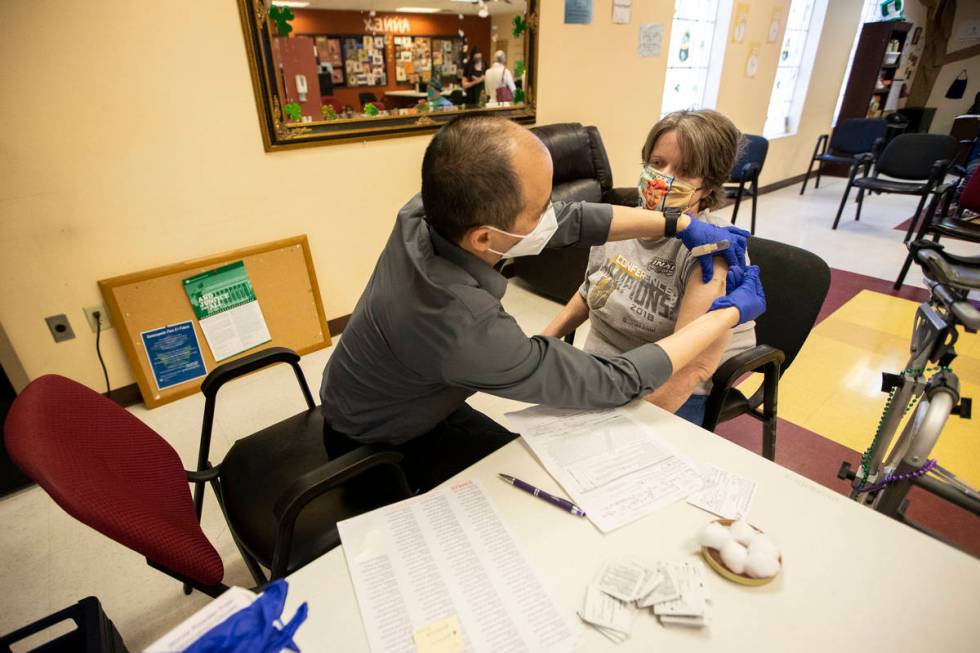 Alex Vong, left, pharmacy manager at Albertsons, administers the second dose of the COVID-19 va ...