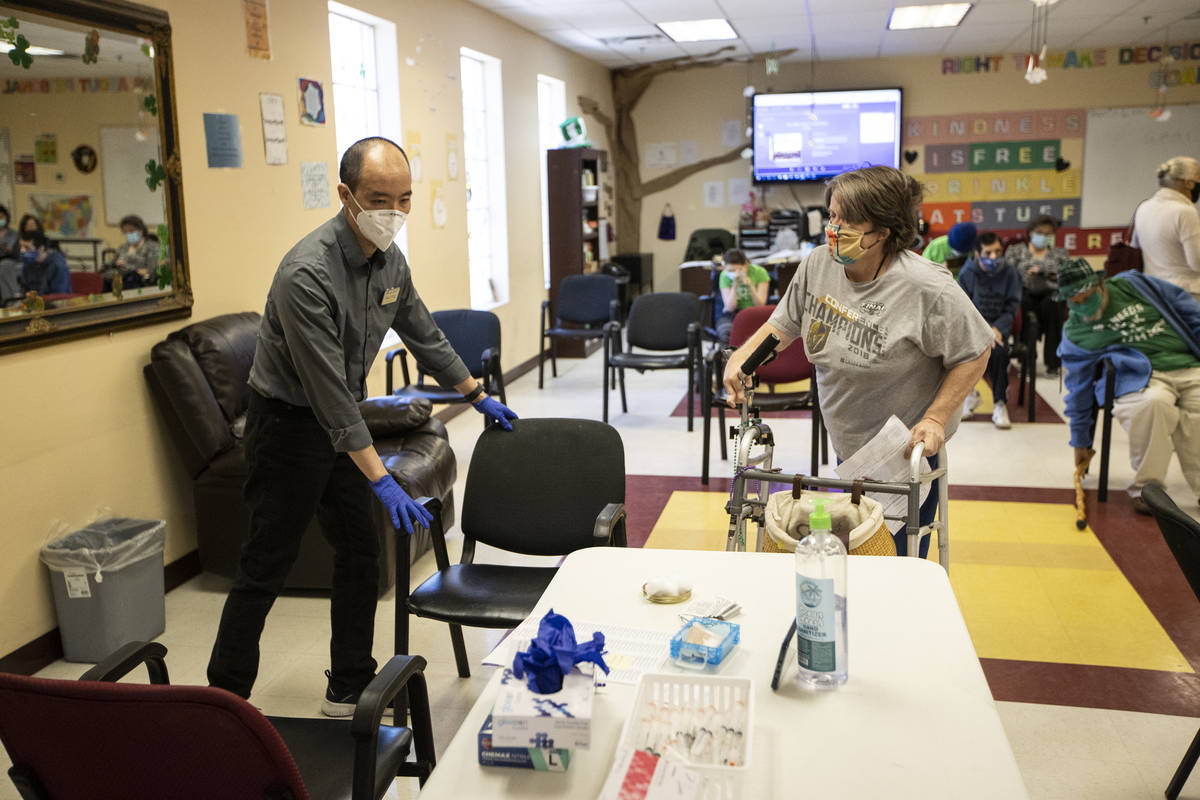 Alex Vong, left, pharmacy manager at Albertsons, assists Elaine Triplett to a chair to receive ...