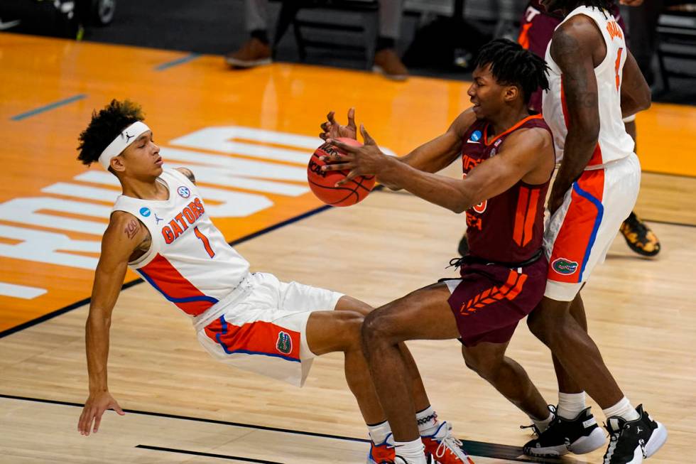 Florida guard Tre Mann (1) draws the charge from Virginia Tech Hokies forward Justyn Mutts (25) ...