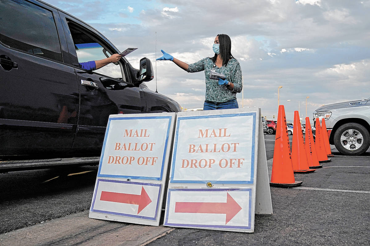 A county worker collects mail-in ballots in a drive-thru mail-in ballot drop off area at the Cl ...