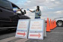 A county worker collects mail-in ballots in a drive-thru mail-in ballot drop off area at the Cl ...
