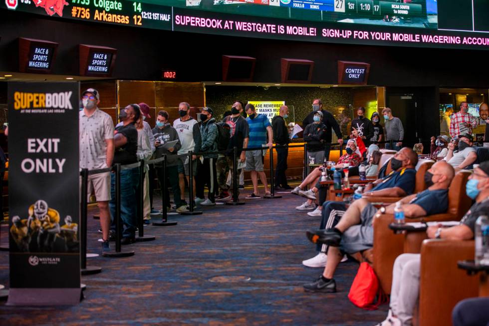 Bettors wait in line as others enjoy the games above during opening day of NCAA Tournament play ...