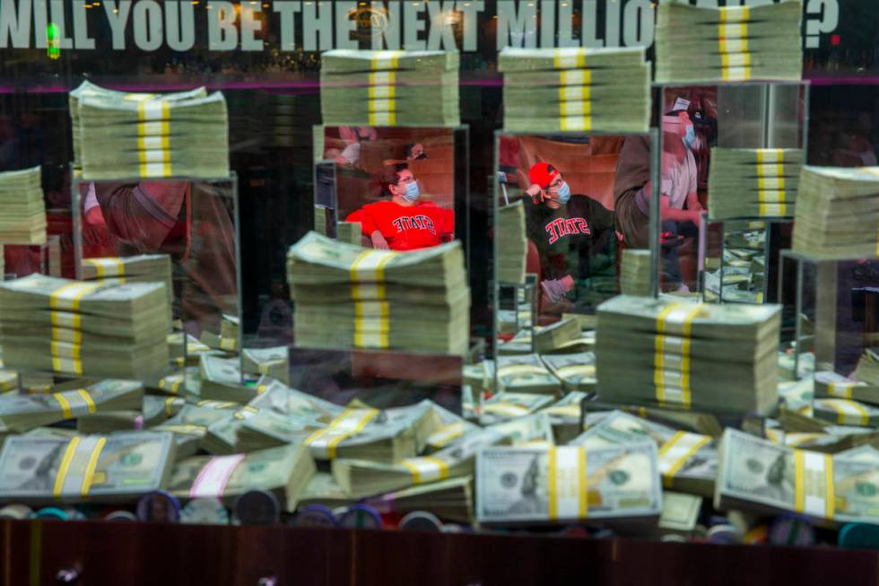 (From left) Aaron and Matt Tanner of Tulsa are reflected in the glass of a money case as they w ...