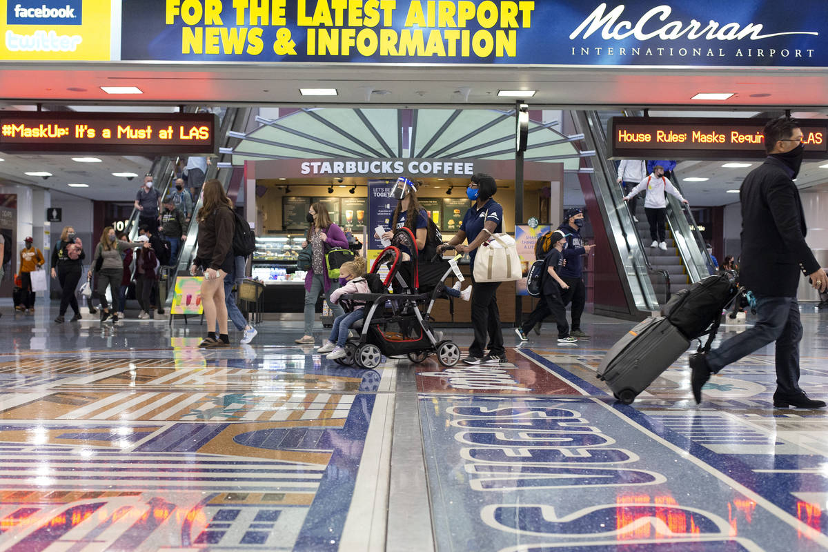 People move throughout baggage claim, wearing personal protective equipment to prevent the spre ...