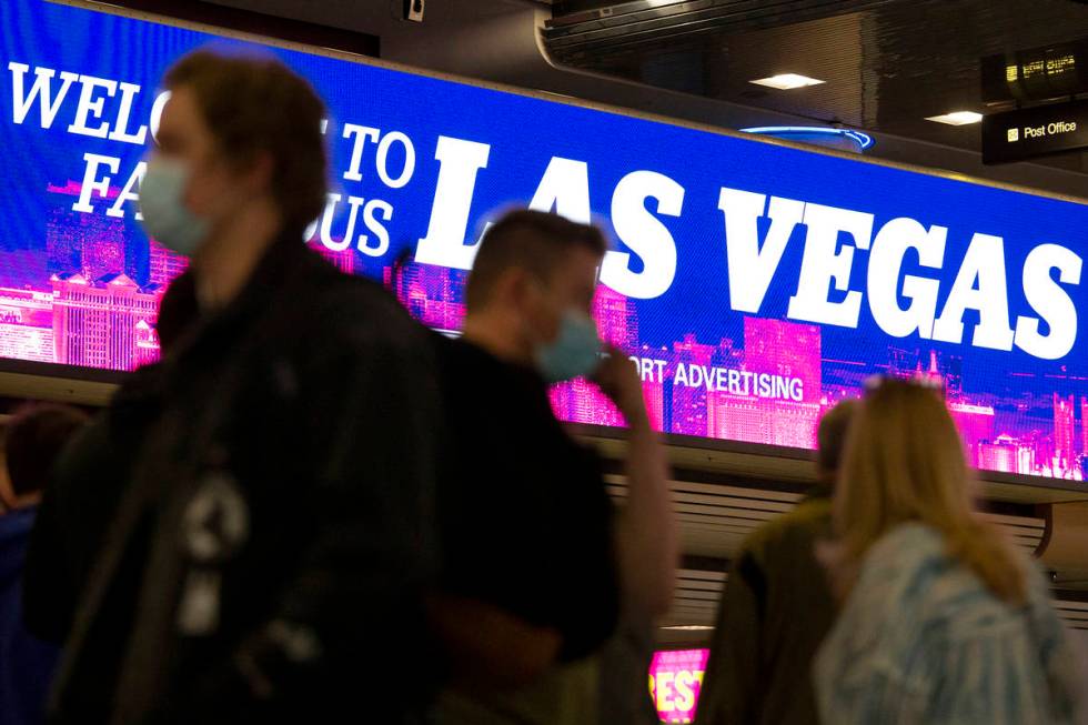 People move throughout baggage claim, wearing personal protective equipment to prevent the spre ...