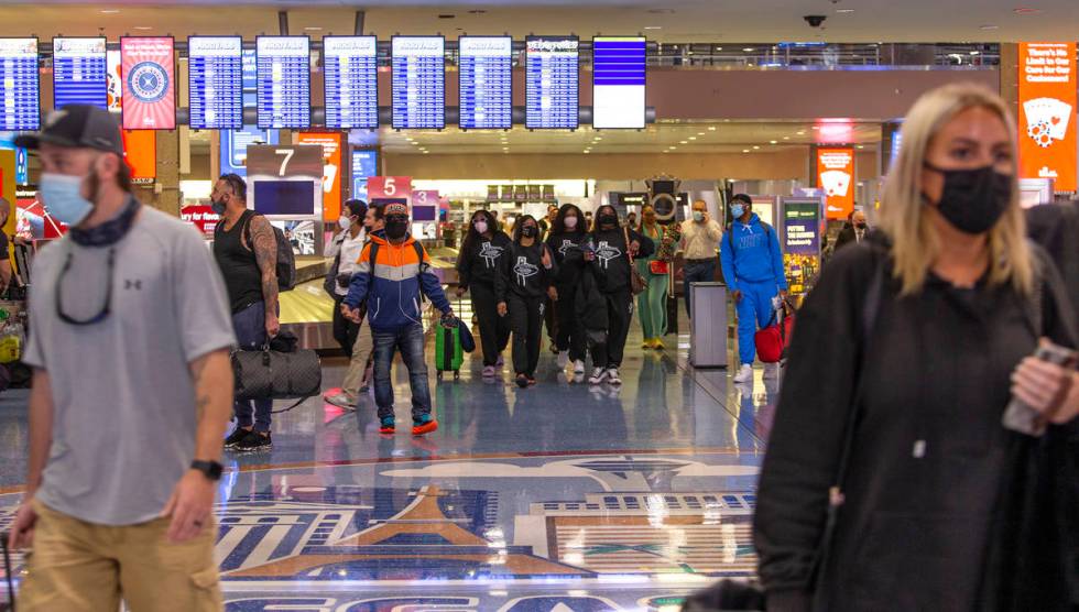 People move throughout baggage claim, wearing personal protective equipment to prevent the spre ...