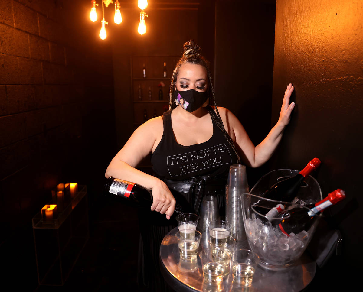 Sydni Sayles pours sparkling wine for guests arriving on reopening night at Cork and Thorn in d ...