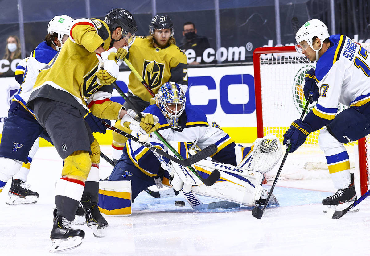 St. Louis Blues goaltender Jordan Binnington, center, and Jaden Schwartz, right, defend the net ...