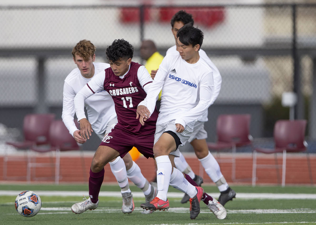 Faith Lutheran midfielder Preston Rincon (17) runs for the ball flanked by Bishop Gorman Nathan ...