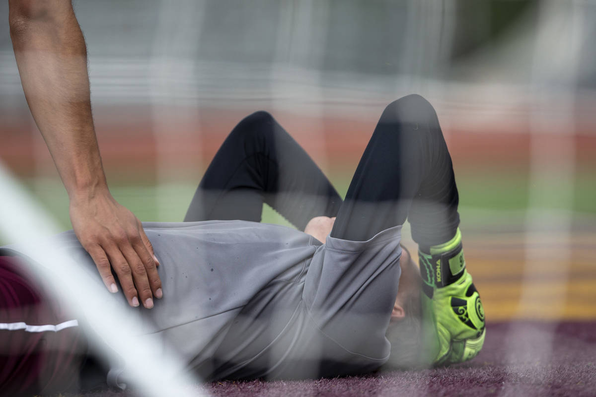 Faith Lutheran goalkeeper Landon Amick (0) is comforted by a teammate after letting a Bishop Go ...