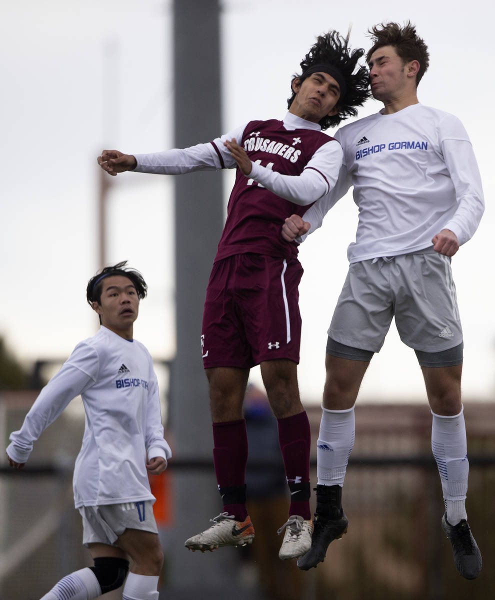 Faith Lutheran forward Ari Sirvent (14) and Bishop Gorman defender Keegan Brooks (4) jump for a ...