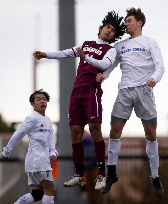 Faith Lutheran forward Ari Sirvent (14) and Bishop Gorman defender Keegan Brooks (4) jump for a ...