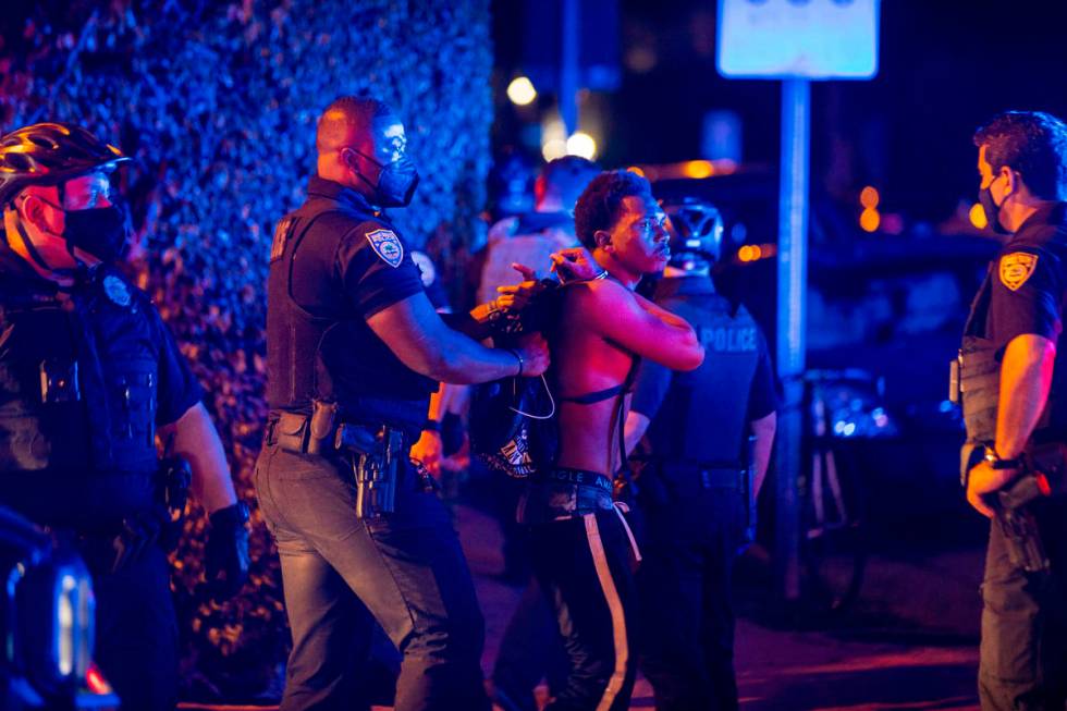 A man is arrested while out a few hours past curfew in Miami Beach, Fla., on March 21. Miami Be ...