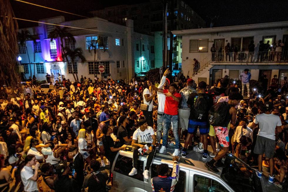 Crowds defiantly gather in the street while a speaker blasts music an hour past curfew in Miami ...