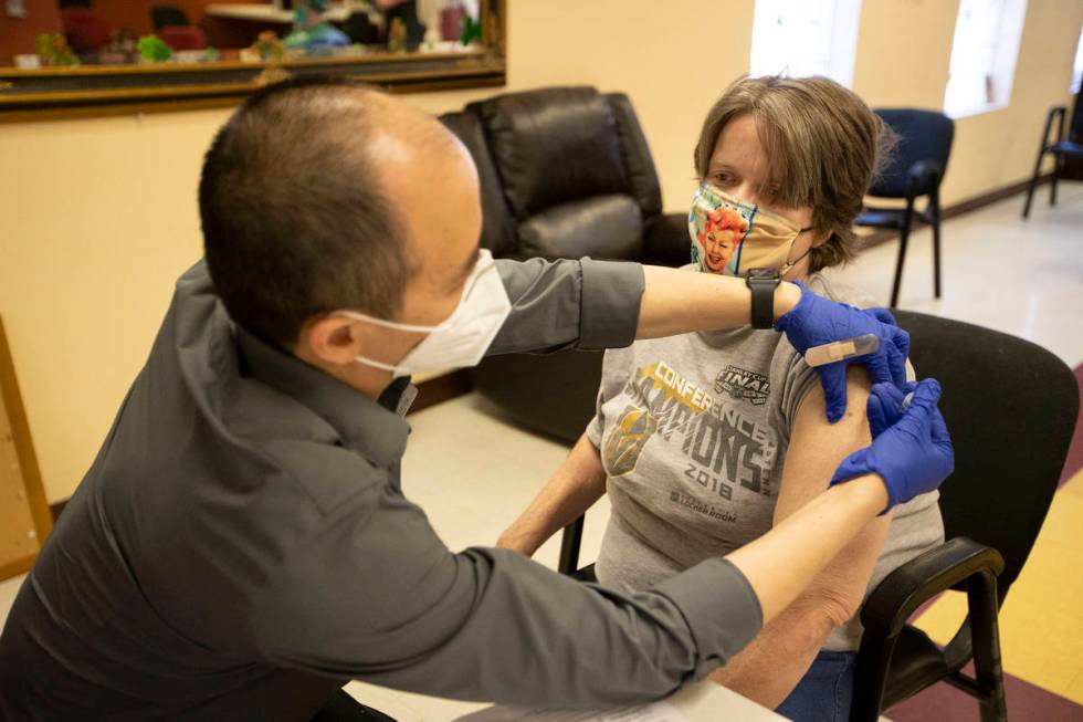 Alex Vong, left, pharmacy manager at Albertsons, administers the second dose of the COVID-19 va ...