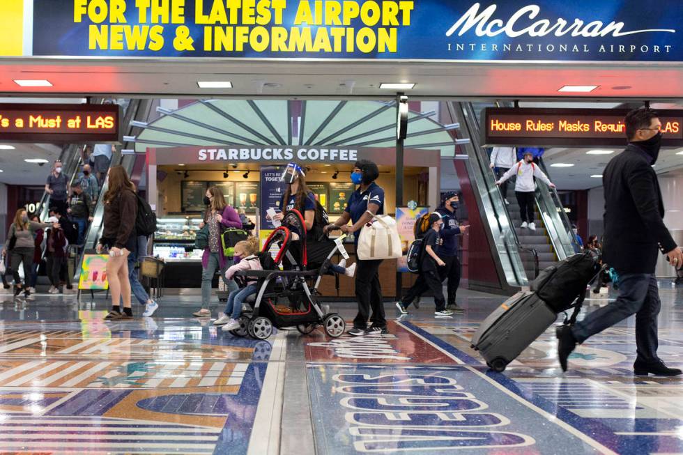 People move throughout baggage claim, wearing personal protective equipment to prevent the spre ...