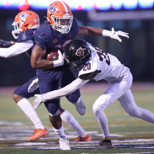 Bishop Gorman's Sebastian Shannon (23) is tackled by Faith Lutheran's Chandler Silva (20) durin ...