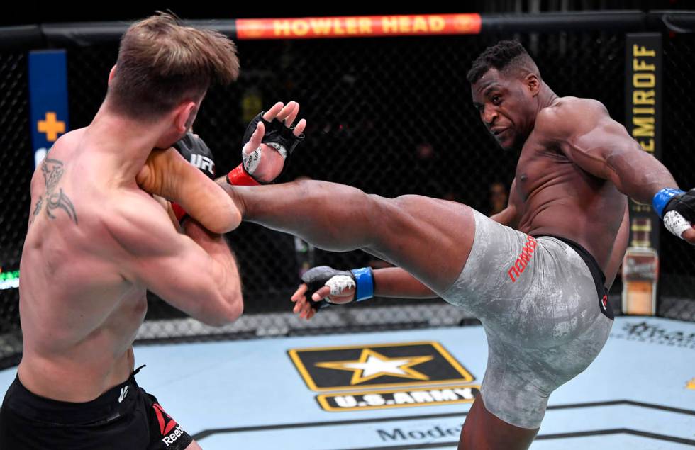 Francis Ngannou of Cameroon kicks Stipe Miocic in their UFC heavyweight championship fight duri ...
