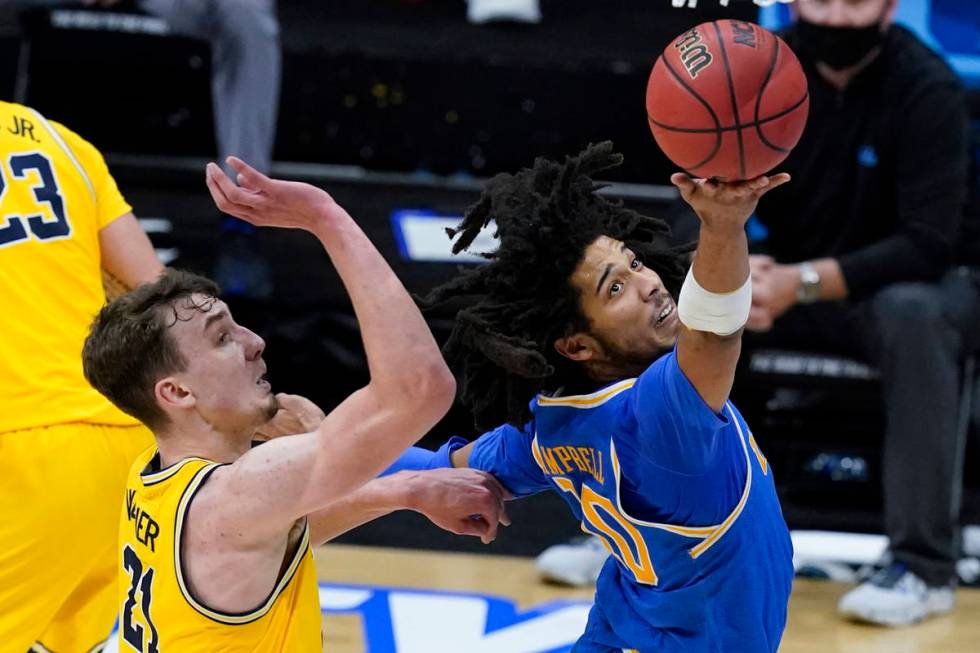 UCLA guard Tyger Campbell drives to the basket in front of Michigan guard Franz Wagner, left, d ...