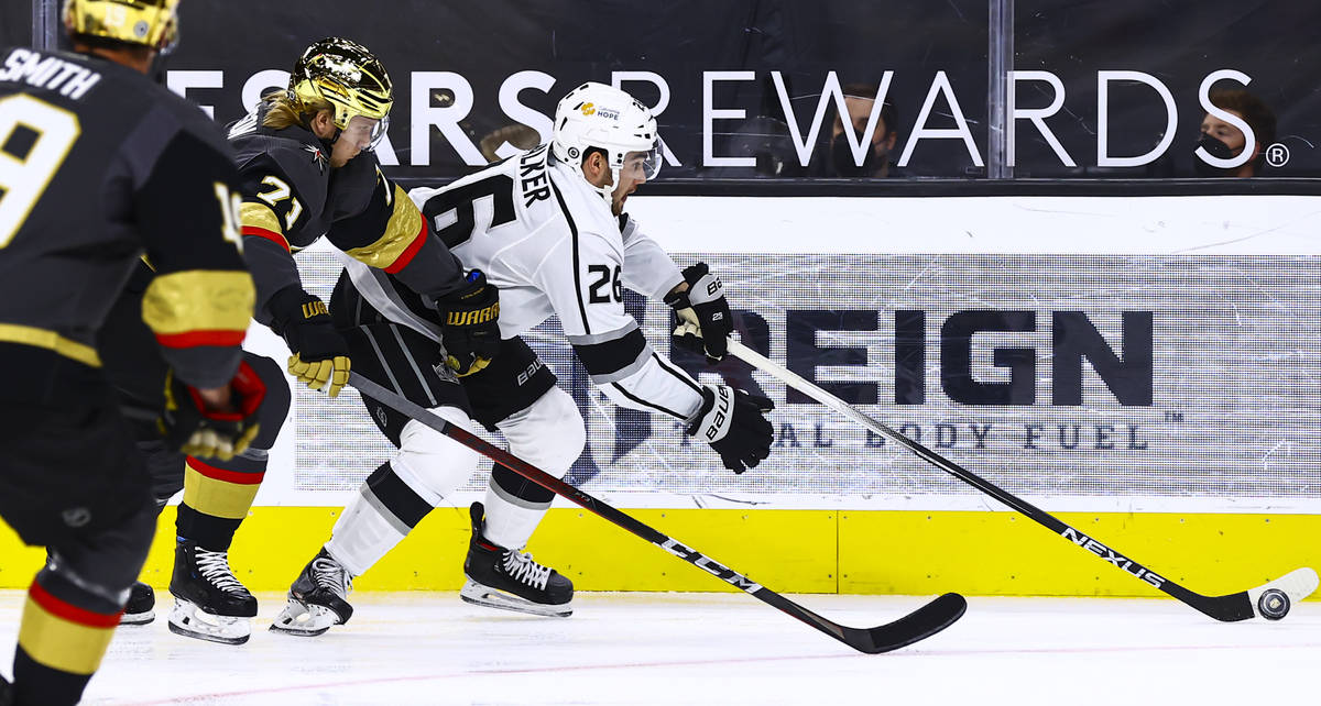 Los Angeles Kings' Sean Walker (26) skates with the puck under pressure from Golden Knights' Wi ...