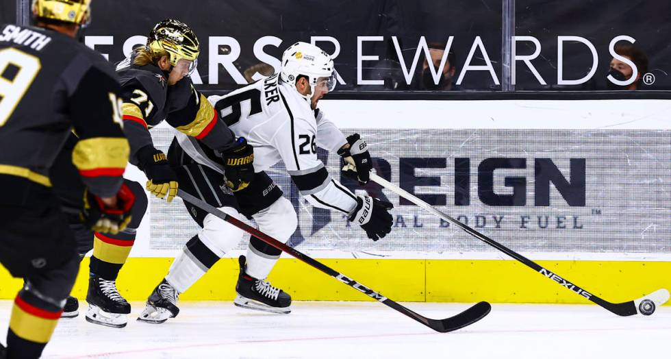 Los Angeles Kings' Sean Walker (26) skates with the puck under pressure from Golden Knights' Wi ...