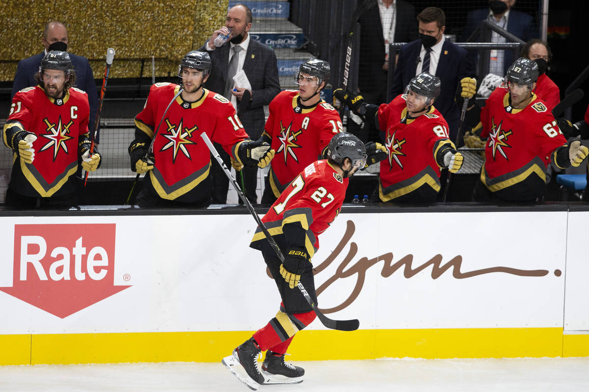 Golden Knights defenseman Shea Theodore (27) is congratulated by the team after scoring a goal ...