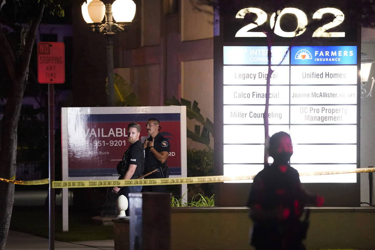 Police officers stand outside a business building where a shooting occurred in Orange, Calif., ...