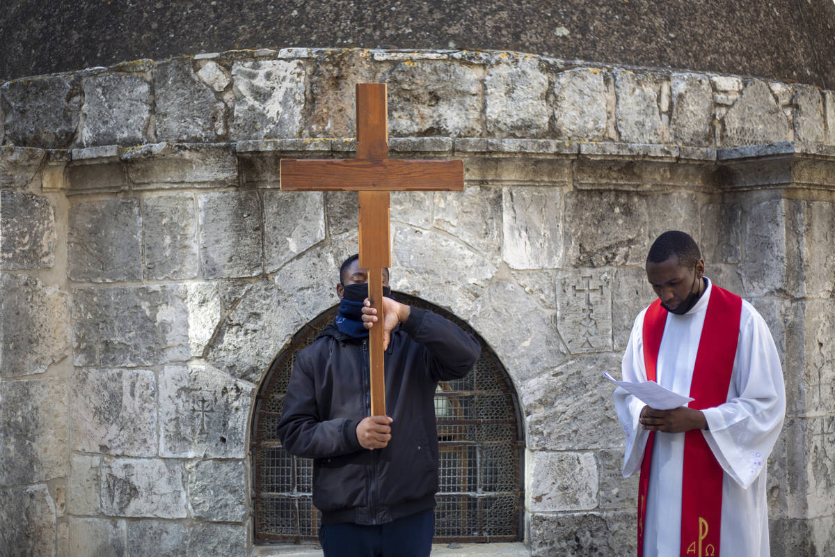 Christians, one carrying a cross, pray during the Good Friday procession after walking in the V ...