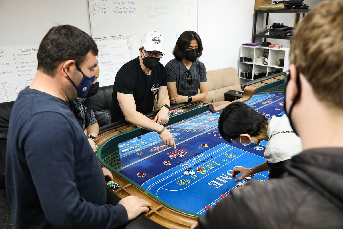 David Noll, managing director for CEG Dealer School, center, teaches students how to play craps ...